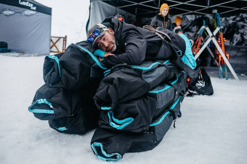 Man resting on stacked ski bags at a winter event